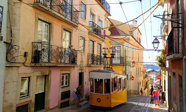 Foto av en av de berømte trikkene i en gate på Lisboa i dagslys.