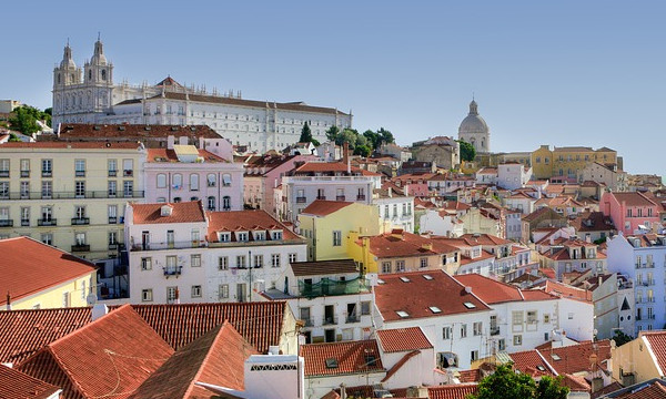 Foto av Alfama-distriktet i Lisboa, med fargerike, malte murhus i en skråning.